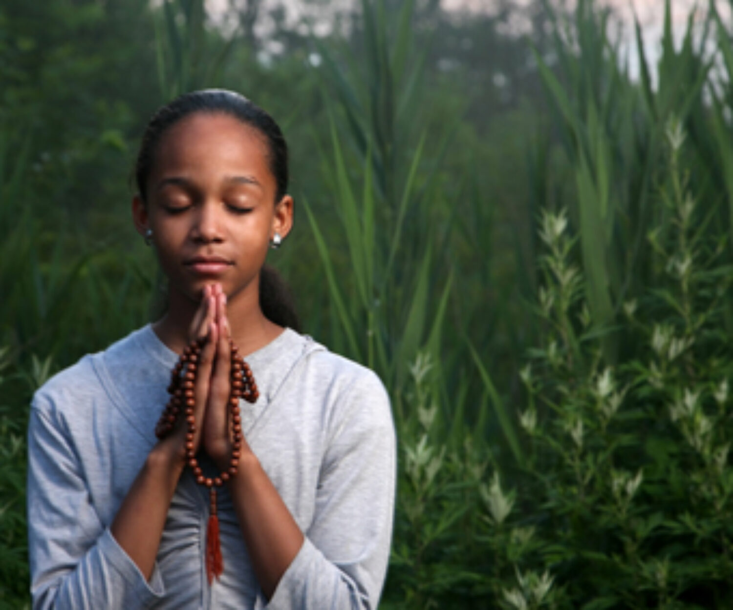 Teenage girl praying outdoors at twilight